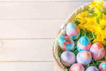 Close Up of Basket of Hand Painted Easter Eggs with Daffodils on Table From Above with Copy Space