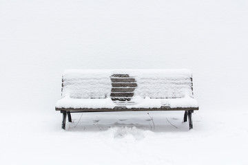 snow-covered wooden bench with an imprint of someone, who had been sitting in the middle; winter...