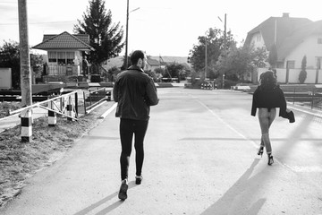 man and woman running to the railroad crossing