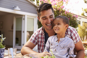 Obraz premium Father And Son Eating Outdoor Meal In Garden Together