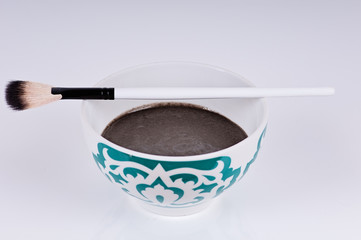bowl of black clay mask with brush at home skin care