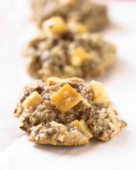 Freshly baked apple, oatmeal and linseed cookies on baking paper, photographed with natural light (Selective Focus, Focus in the middle of the first cookie)