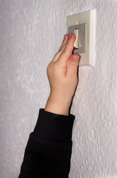 Mano de ni&ntilde;o accionando interruptor de la luz
