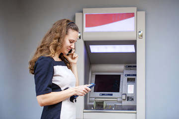 Young woman inserting a credit card to ATM