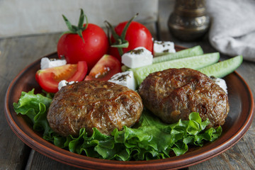  fried cutlets in plate with vegetables on wooden table