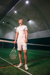 Delighted handsome tennis player going to play