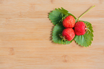 Ягоды клубники на листьях на деревянном фоне