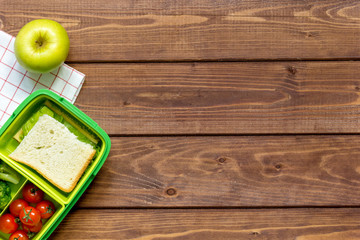 green lunch box for kid on wooden background top view
