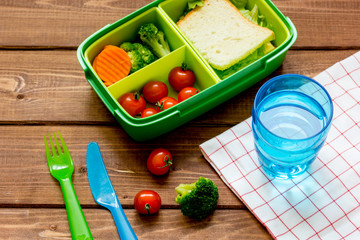 lunch box for kid with fresh vegetables on wooden background