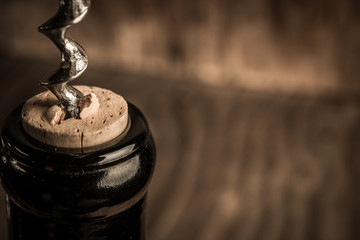 Bottle of wine with corkscrew on wooden background