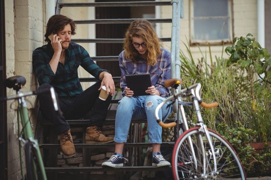 Couple Talking On Mobile Phone And Using Digital Tablet