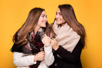 Cheerful twins sisters posing with scarf.