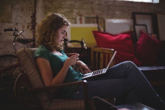 Beautiful mechanic using laptop while having coffee