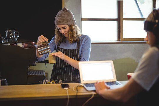 Waitress preparing coffee at counter