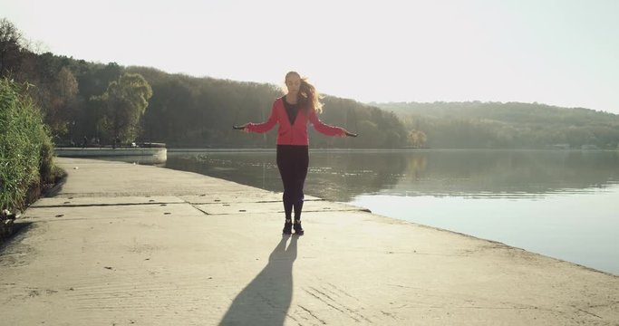 4K Energetic girl skipping outdoors in a park near lake on a nice day, in slow motion. Red Epic