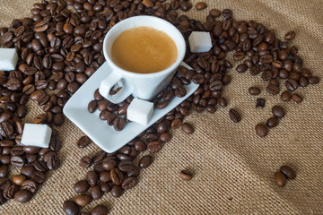 Cup and grain of coffee over textile background