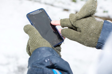 Male hands in gloves using a smartphone