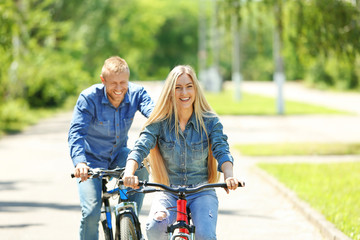 Happy couple riding bicycles in the park