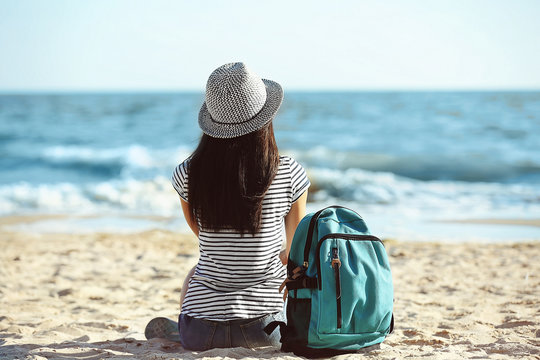 Tourist girl with backpack on beach