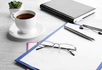 Glasses, clipboard and cup of coffee on wooden table. Healthy eyes concept