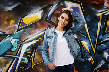 Pretty young woman in blank t-shirt against graffiti wall