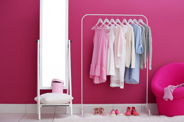 Fashionable clothes hanging on rack at modern dressing room