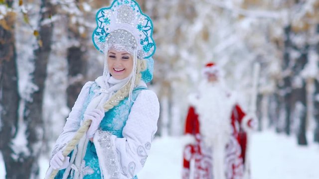 Beautiful Snow Maiden in the foreground playing with her hair and Father Frost in the background