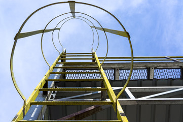 Caged ladder leading up and blue sky © mrfiza