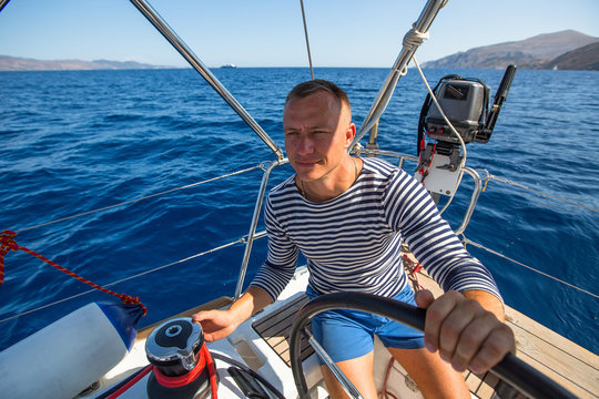 Young man at the helm of his yacht.