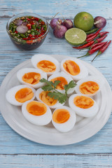 Boiled eggs and fish sauce with chili lemon and shallots on blue wood floor. Thai food