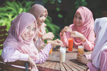 pretty asian muslim woman having fun in cafe together with frien