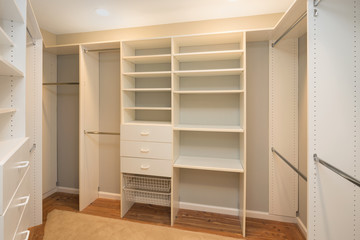 Big empty walk in wardrobe in luxurious house with installed shelves.
