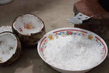 Close up blade of coconut grater with coconut grated in bowl , Shallow depth of field , light and shadow