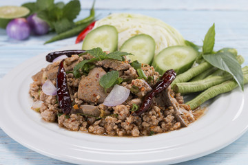 spicy minced pork salad on the wooden table in blue, thai food