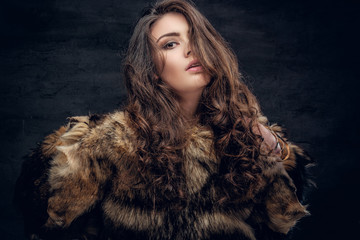 Sensual brunette female dressed in a fur coat.