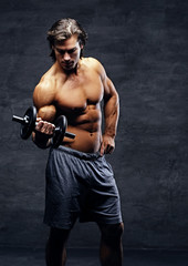 Obraz na płótnie Canvas Shirtless muscular male holds dumbbell.