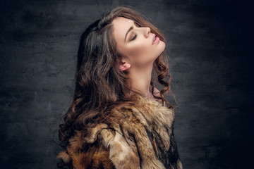 Sensual brunette female dressed in a fur coat.