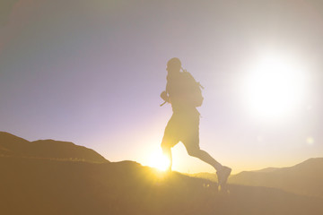 Man's Silhouette Running In A Sunset With Mountain Range As A Ba
