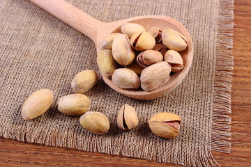 Pistachio nuts with spoon on wooden table, healthy eating