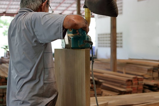 Rear view of carpenter using belt sander in carpentry workshop