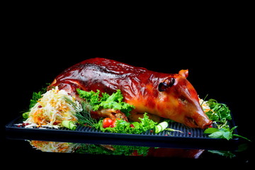 baked piglet on black background