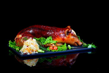 baked piglet on black background