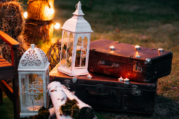 Vintage lanterns on old suitcases, free space. Beautiful composition in retro style illuminated with lamp, evening time. Creative, design, romantic concept