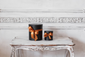 Wrapped gift black boxes with ribbons as Christmas presents on a table luxury white wall design...