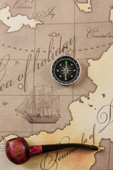tobacco pipe and compass on map