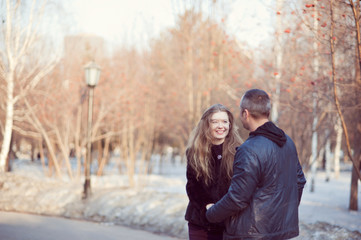 Fototapeta premium Young woman holding a man's hands, looks at him and smiles, cool weather, Park.