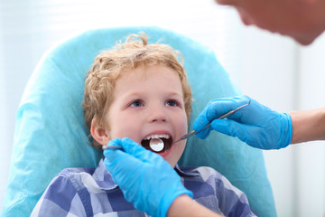 Close-up of little boy opening his mouth wide during inspection of oral cavity by dentist.