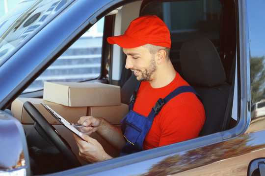 Delivery man checking list in car with parcels