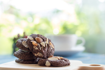 Chocolate cookie on blue wooden table and green garden background.