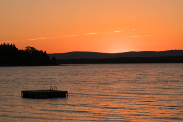 sunrise over a lake with a raft and mountains in the background